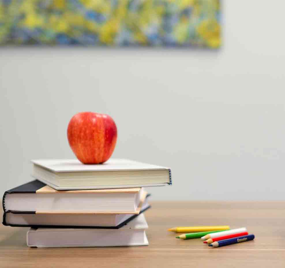 Schoolbooks with an apple on top in Classroom