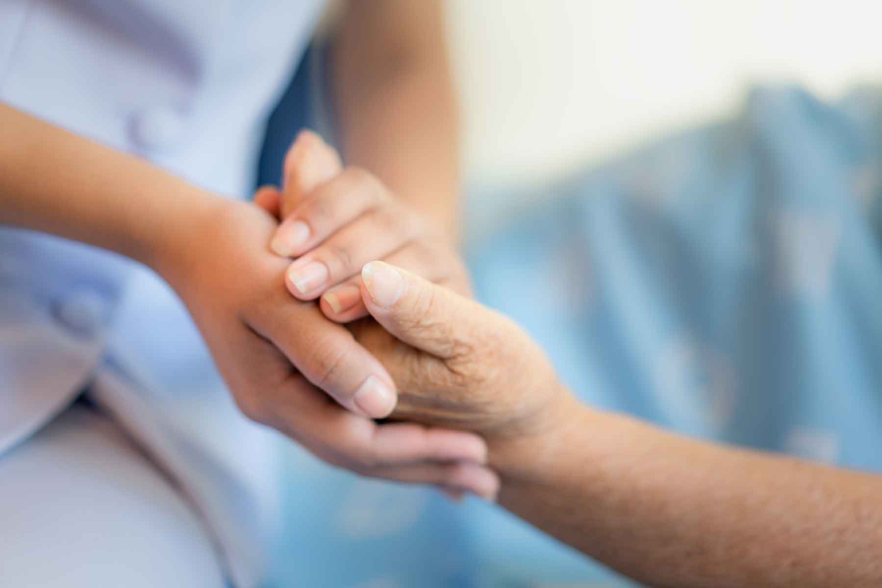 Person holding elderly persons hands